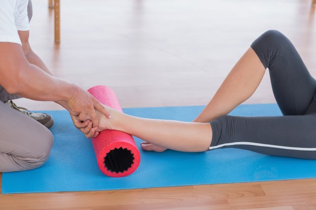 Trainer working with woman on exercise mat