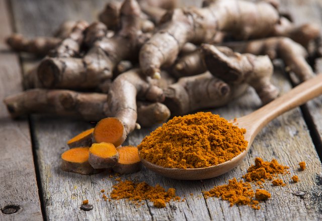 pile of fresh turmeric roots on wooden table