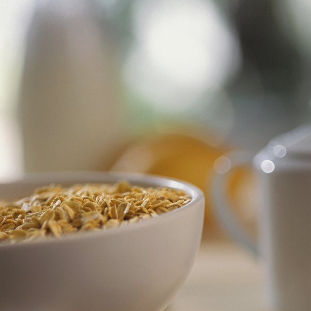 Bowl of cereal with spoon and edge of plate with pastry on it, close-up