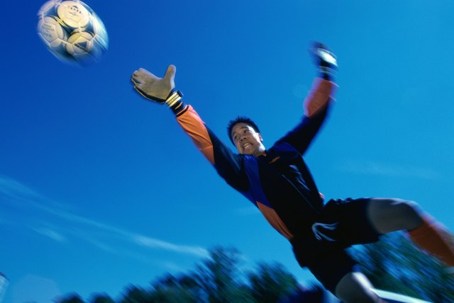 Low angle view of a teenage goalie reaching for the ball