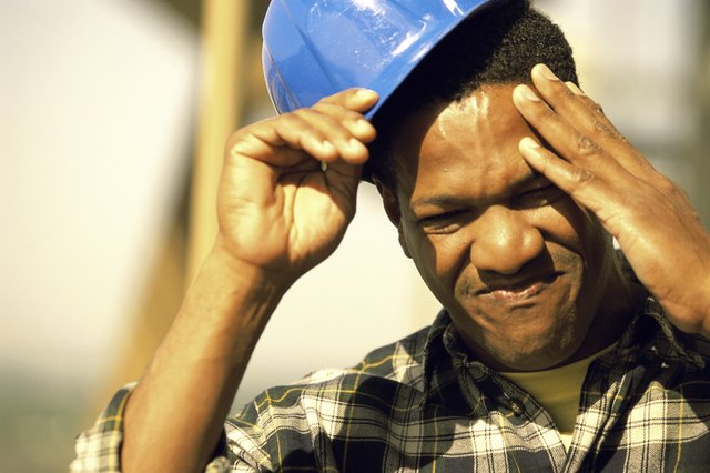 Close-up of a construction worker touching his head and removing his hardhat