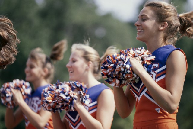 Side profile of three cheerleaders holding pom-poms