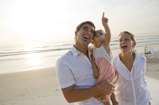 Cheerful young couple with daughter on the beach