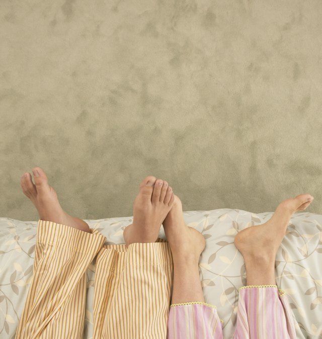 Low section view of a young couple lying on a bed