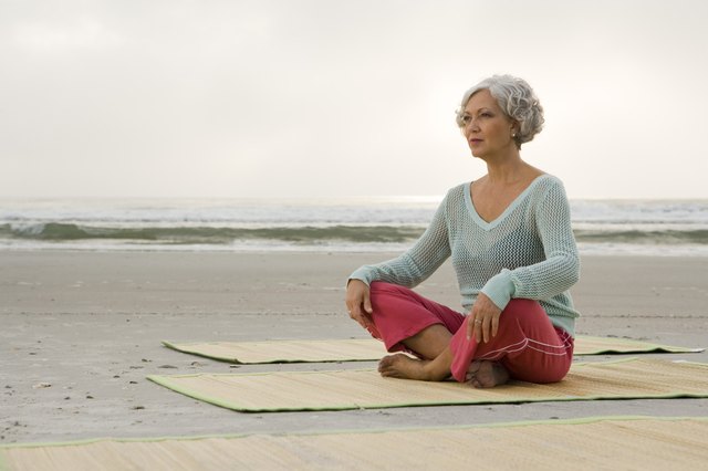 Mature woman exercising on a mat at the beach