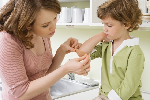 Mother putting bandage on daughter's cut
