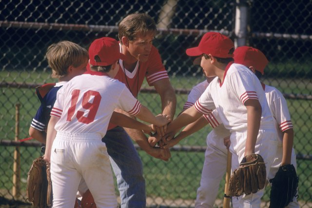 Boys and softball coach with hands together in huddle