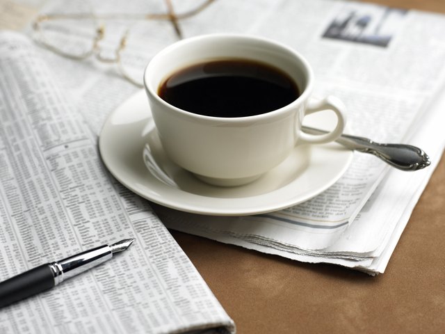 Cup of coffee, pen and financial newspaper