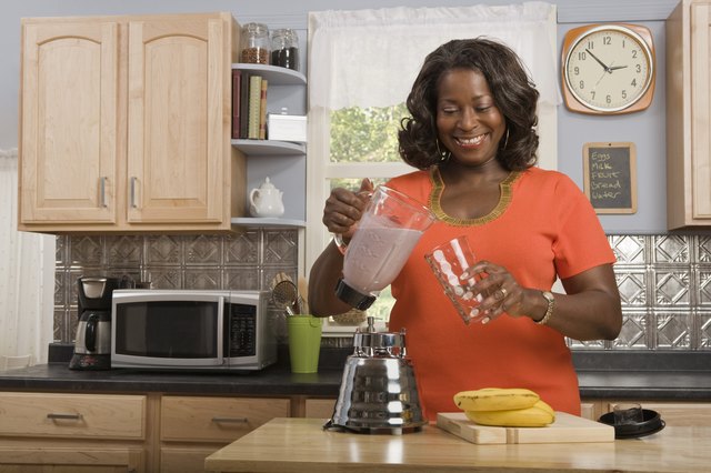 Woman in kitchen making smoothie