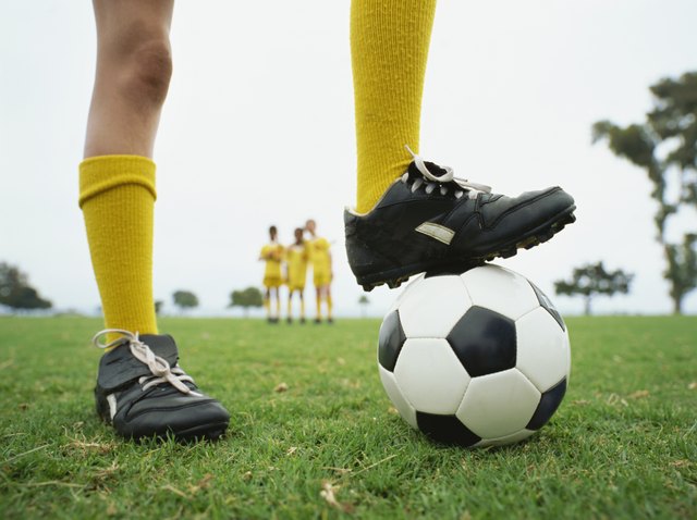 low section view of a person with his one leg on a soccer ball