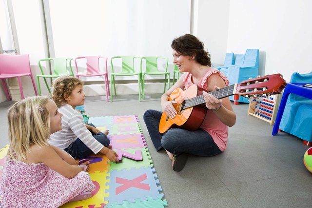 Teacher playing guitar for students
