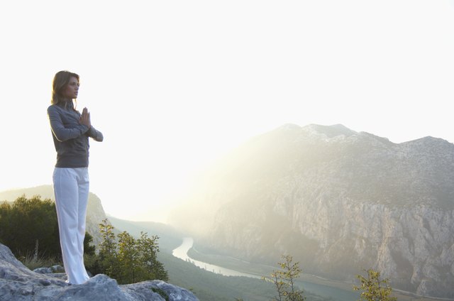 Young woman standing in mountain landscape, hands pressed together