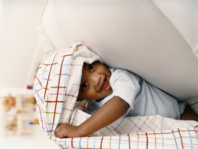 Young Boy Sitting on a Chair and Playing Under a Sheet
