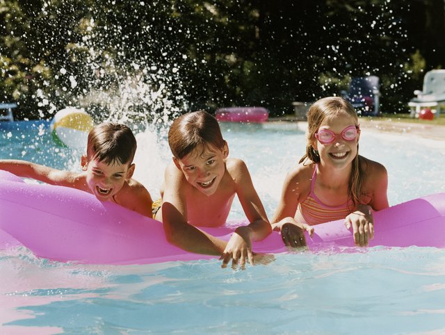 Three children in a Swimming Pool Playing With an Air Bed