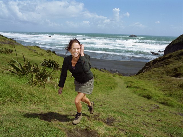 Woman walking up hill, beach in background
