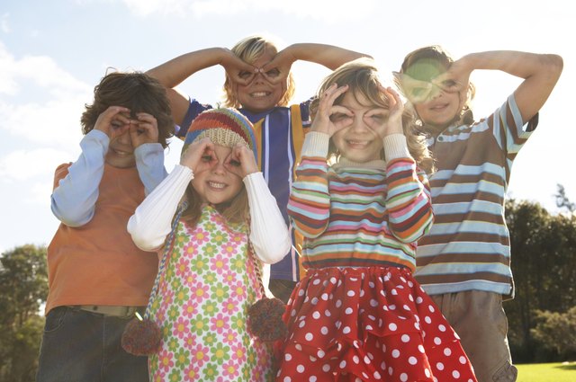 Five children (7-12) with fingers over eyes, portrait (lens flare)