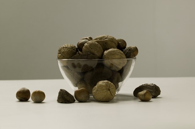 Assortment of nuts lying in glass bowl and around, studio shot, close-up