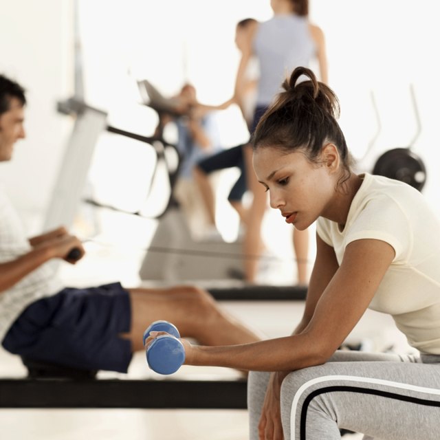 side view of a woman working out with a dumbbell at the gym