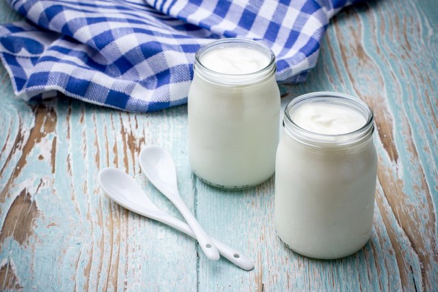 Two yogurt glass on wooden board with spoon