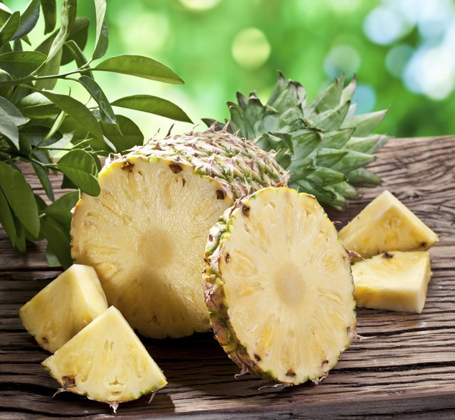 Pineapple with slices on a wooden table.
