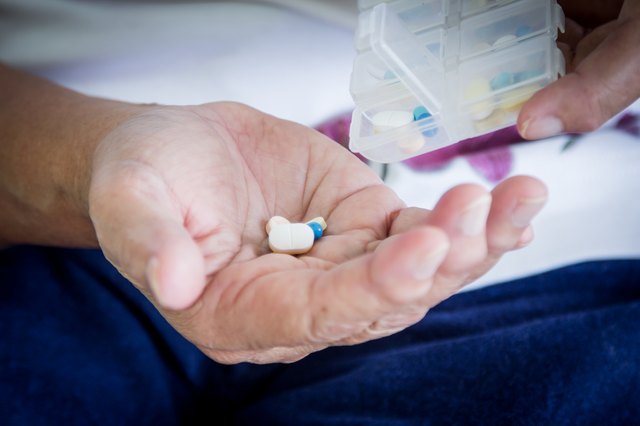 old woman hand pouring pills from a pill reminder box