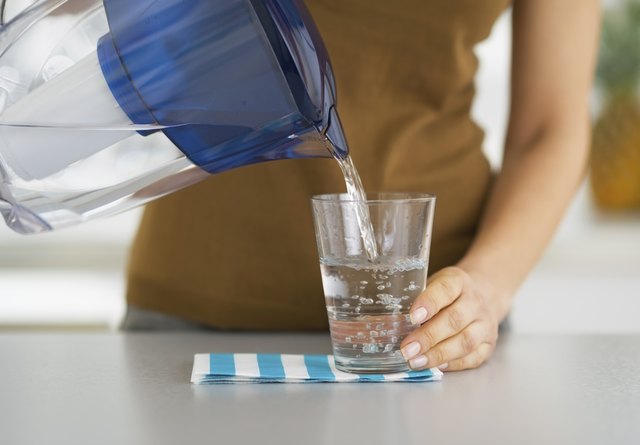 Closeup on housewife pouring water into glass