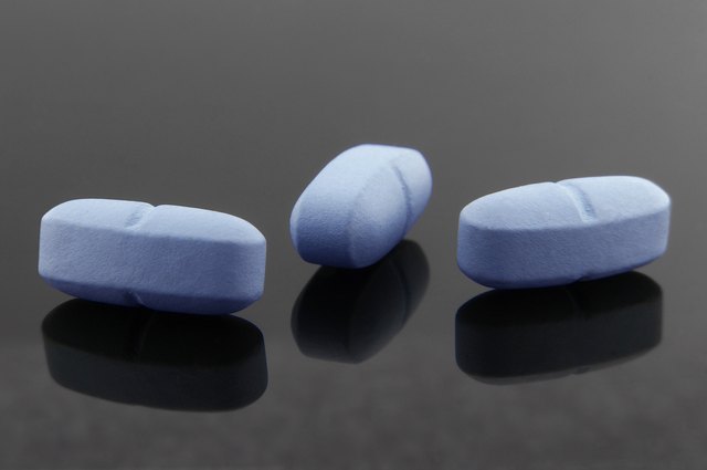 Blue pills and your reflections on dark background.