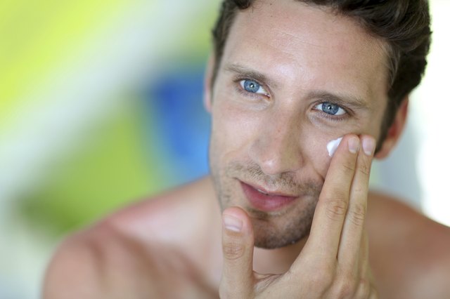 Portrait of man applying cream on his face