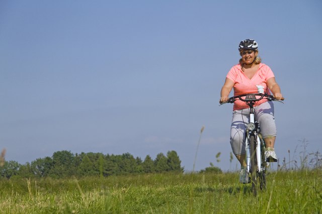 Mature woman cycling through field