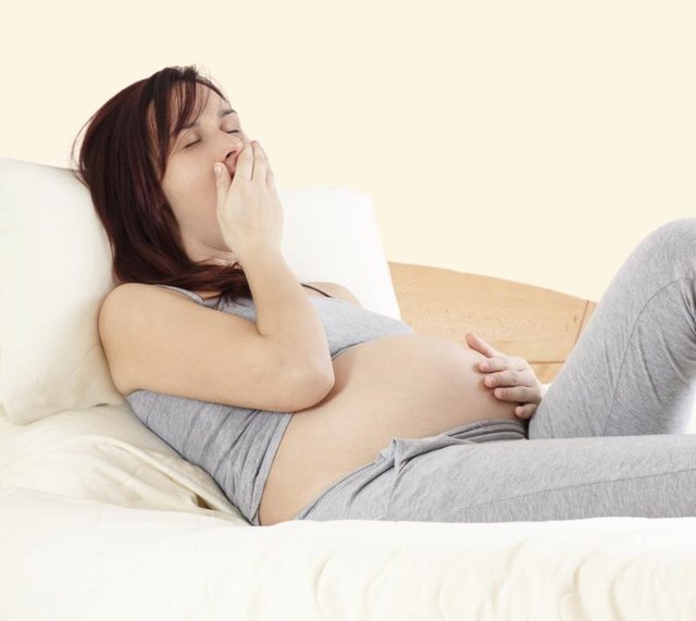 Tired young pregnant woman yawns.