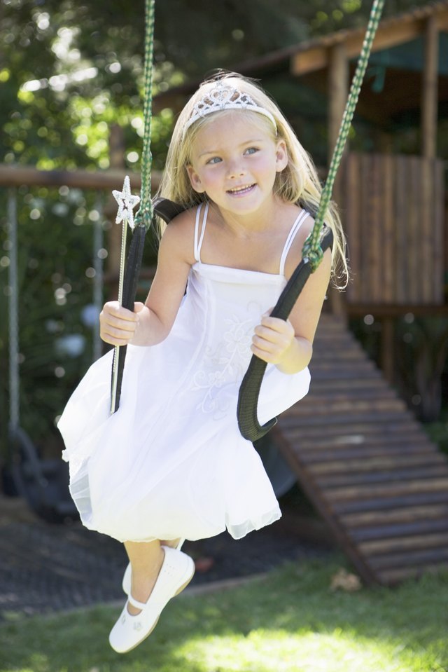 Girl in fairy princess costume sitting in swing