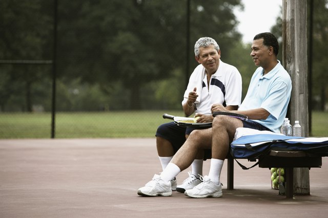 Multi-ethnic men talking on tennis court
