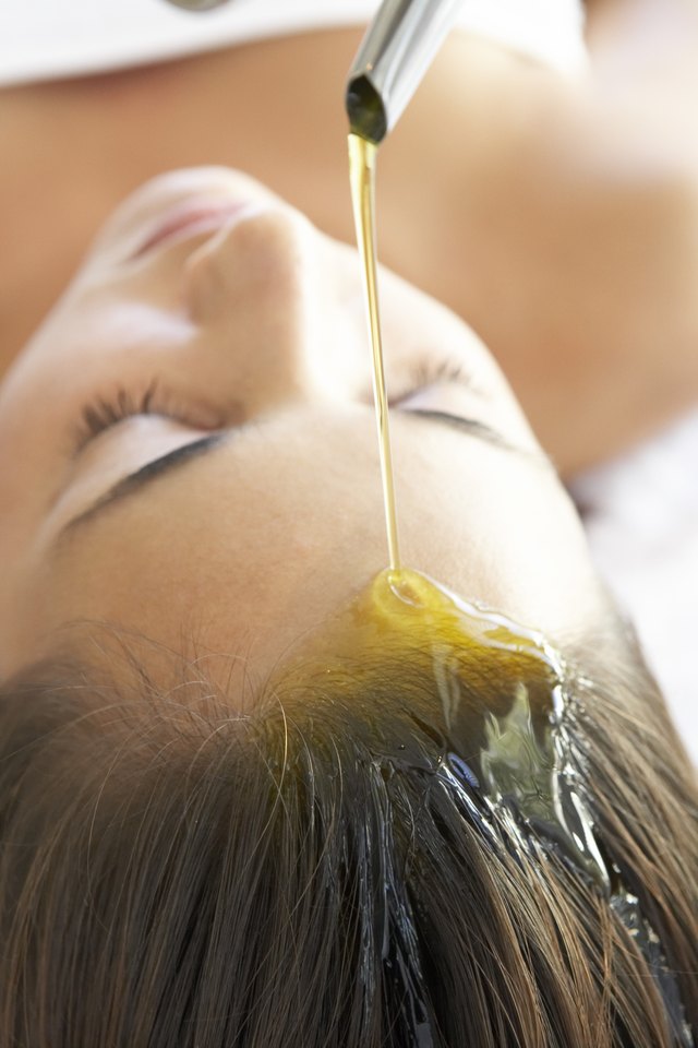 Oil pouring onto woman's forehead and hair