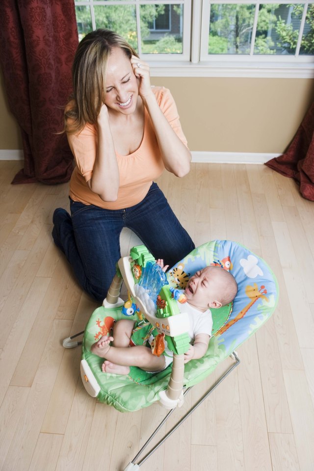 Mother covering ears from crying baby