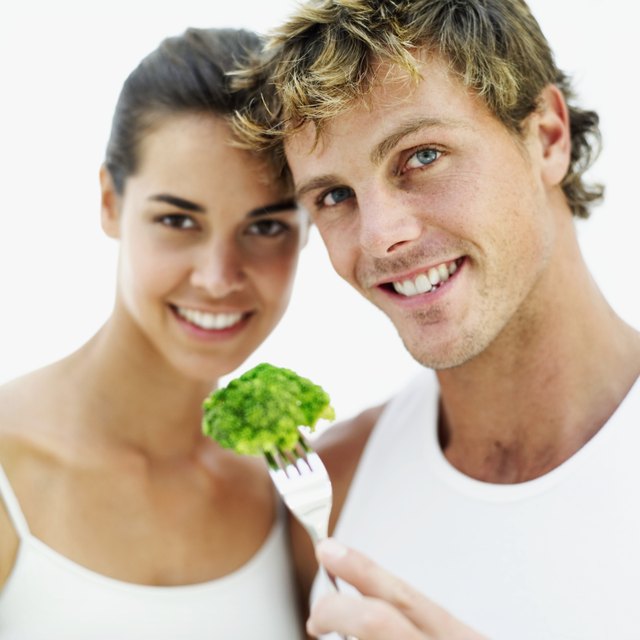 young couple holding a piece of broccoli on a fork