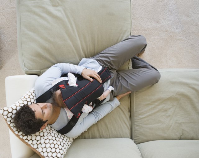 Hispanic father sleeping on sofa with baby