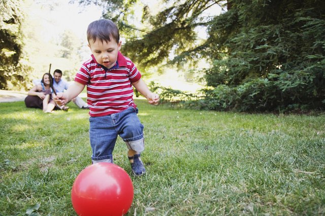 Toddler boy kicking red ball