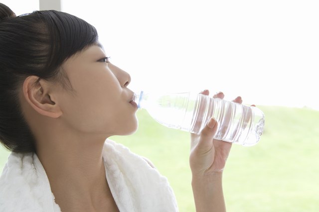 Close up of a young woman drinking water, side view