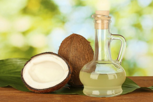 decanter with coconut oil and coconuts on green background