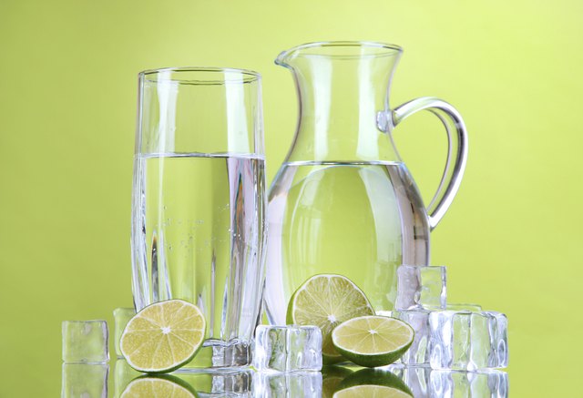 Glass pitcher of water on green background