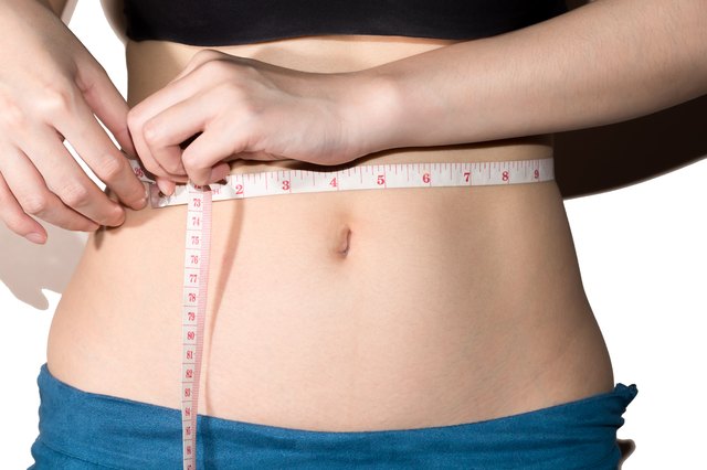 Young slim woman measuring waist circumference