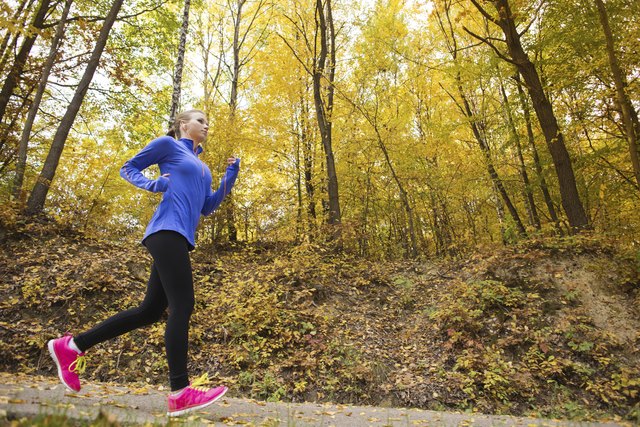 Active and sporty woman runner in autumn nature