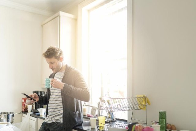 Man using mobile phone with forward neck tilt while drinking coffee.