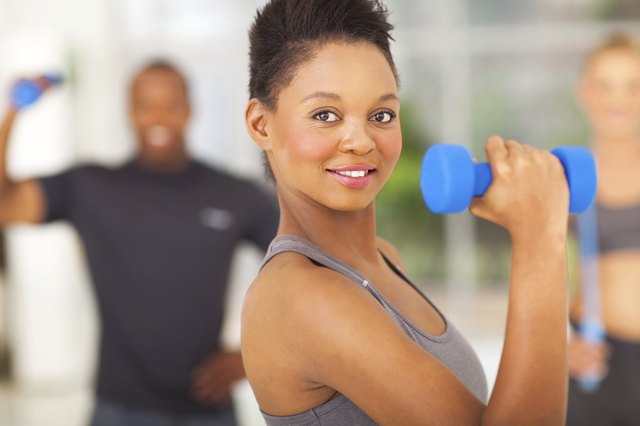 fit african woman lifting dumbbell