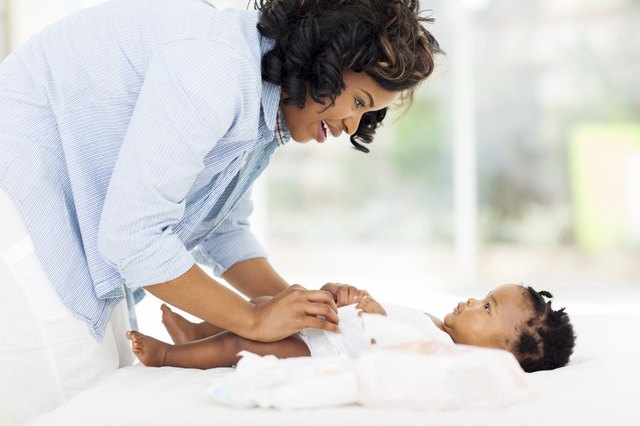 african american mother changing baby's diaper