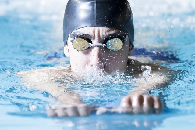 young male swimmer swimming with a swim board