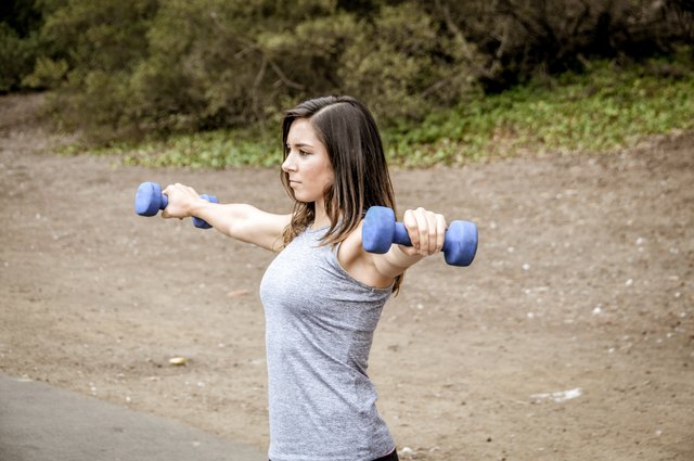 Athletic woman lifting dumbbells in park