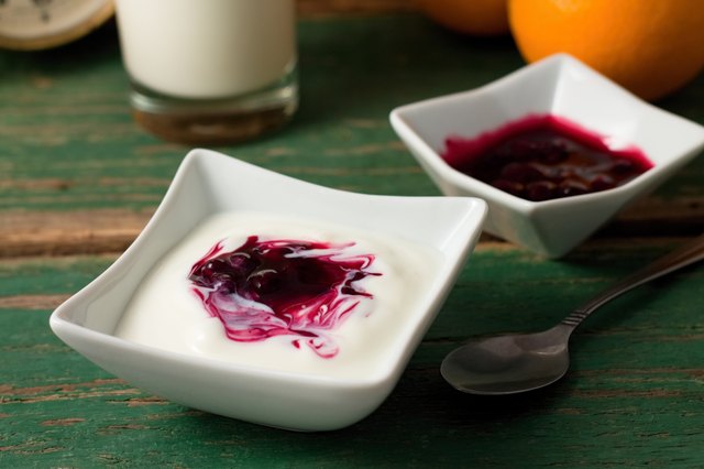 Red berry fruit in white yogurt placed with bowl