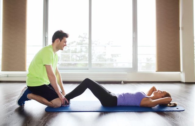fitness, sport, training, teamwork and people concept - woman with personal trainer doing sit ups in gym