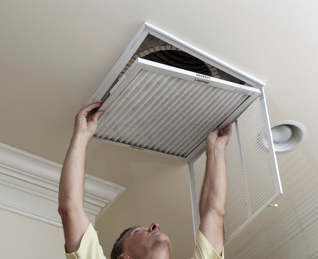 Senior man opening air conditioning filter in ceiling